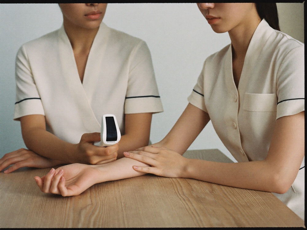 Therapist holding skin-analysis diagnostic light to guest forearm